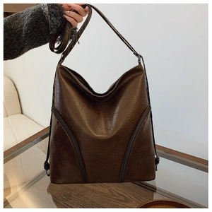 Detail of soft dark brown vintage leather tote with decorative front zipper pockets