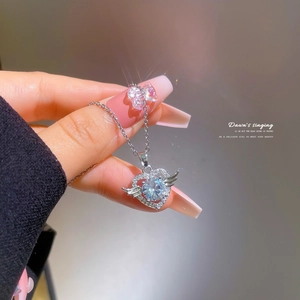Macro detail of silver angel heart necklace featuring a large crystal and pavé wings