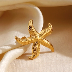 Golden starfish open ring with textured surface on elegant beige silk background