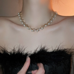 Detailed view of leaf shaped gold necklace with pearls and rhinestones on a model