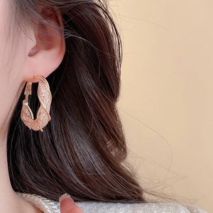 Detailed close-up of rose gold textured mesh hoop earrings worn by a model