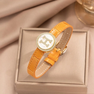 Close-up of orange leather bracelet with golden H logo and white shell inlay on gift box