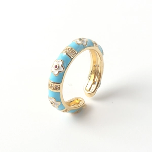 Macro view of blue enamel ring with white flower patterns and zircon inlays on gold band