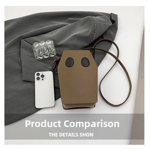 Macro shot of coffin-shaped brown crossbody bag with black oval details on gray suit fabric