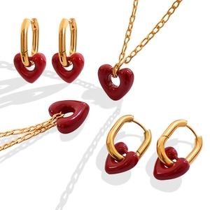 Elegant gold jewelry set featuring red heart necklaces and earrings on a white background