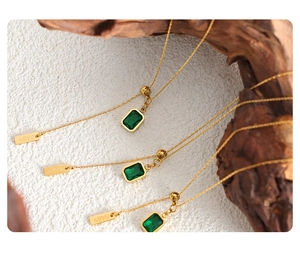 Detailed view of emerald green zircon square pendant and BABY engraved tag on gold necklace