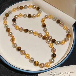 Détail d'un collier vintage français en œil de tigre et perles sur écrin en velours beige