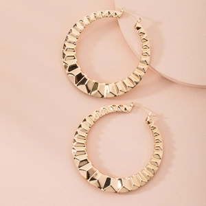 Detailed view of large gold hoop earrings featuring a geometric diamond-cut texture finish