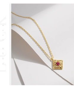Macro detail of retro hollow square pendant with red gemstone and gold chain