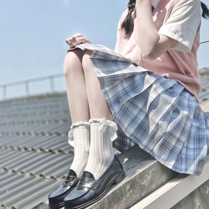 Close-up of white calf socks with bow details paired with blue plaid skirt and loafers