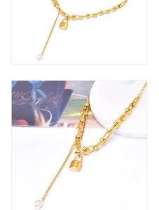 Macro detail of gold U-link chain with LOVE engraved lock pendant and pearl charm