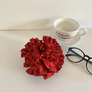 Detailed view of a burgundy pleated satin oversized scrunchie on a white table
