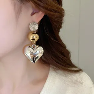 Modern mixed metal dangle earrings with gold spiral disc and large silver heart pendant