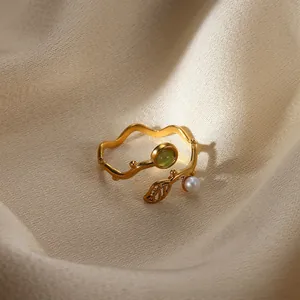 Detail of a wave open ring with a green gem, hollow leaf, and a white pearl on silk