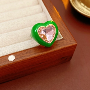Detailed shot of green enamel heart ring with pink zircon on a velvet jewelry display