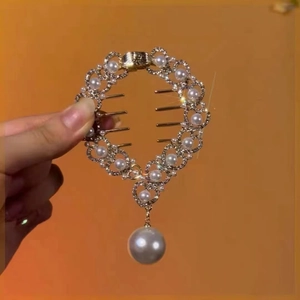 Detail of a golden round hair clip featuring pearls and sparkling rhinestones with a pearl drop