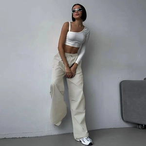 Dettaglio dei pantaloni cargo beige con coulisse e crop top bianco monospalla da donna