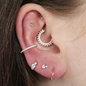 Close-up of gold s925 silver cartilage piercings with heart stud and daisy hoop earrings
