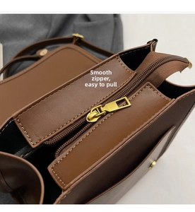 Detail view of smooth golden metal zipper on vintage dark brown leather backpack