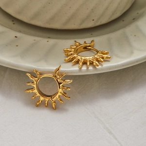Modern 18K gold-plated stainless steel sunburst hoop earrings on ceramic dish