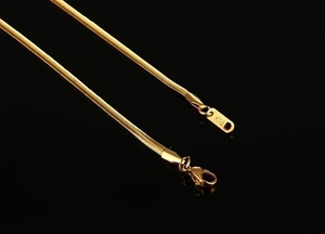 Macro detail of 3mm gold-plated titanium snake chain necklace with K18 engraving
