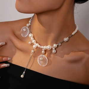 Detail of beaded necklace with pearls, shell charms, and long silver fringe tassels