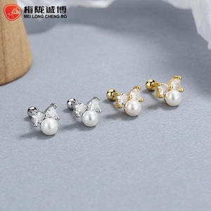 Detailed macro view of 925 silver and gold bow earrings with pearls and zircon stones