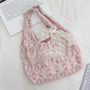 Detail of pink lace shoulder bag featuring white floral embroidery and large ribbon bow
