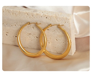 Detailed macro view of polished gold hoop earrings on beige stone and silk background