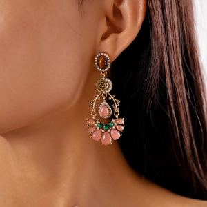 Detail view of vintage gold chandelier earrings with pink resin and tiger eye accents