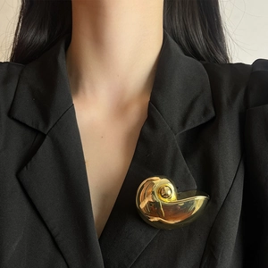 Large vintage gold nautilus shell brooch pinned on a stylish black blazer lapel for women
