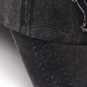 Close-up of distressed denim baseball cap with visible stitching and vintage wear