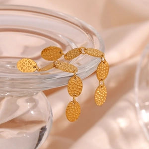 Vue détaillée des boucles d'oreilles ovales dorées avec texture martelée sur soie