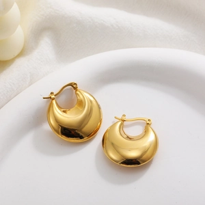 Chunky hollow gold hoop earrings with polished finish on a white ceramic plate
