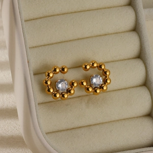 Macro detail of gold plated steel stud earring with center zircon on velvet display