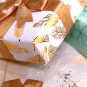 Elegant white gift wrapping paper with gold feather patterns and champagne silk ribbon
