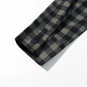 Macro view of dark green plaid shirt cuff featuring double dark round buttons