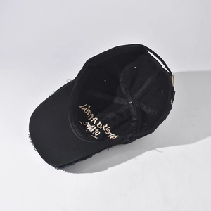 Detail view of washed baseball cap showing golden embroidery and metal buckle closure