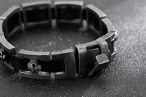 Dettaglio macro del bracciale punk industriale con teschi, maglie vintage e cinturino in pelle
