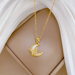 Macro shot of gold moon pendant with white shell and crystal butterfly necklace details