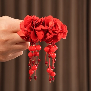 Gros plan de boucles d'oreilles fleurs en soie rouge avec longs pompons et perles boho