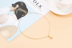 Close-up of golden heart pendant necklace with fine chain on minimalist background