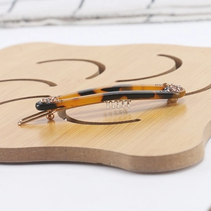 Detail showing amber acetate hair clip with sparkling rhinestones and gold metal base