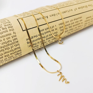 Detail of gold snake chain necklace set with script letter pendants and heart accents