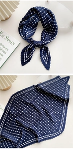 Close-up of navy blue pleated scarf with white polka dots and vertical pleat texture