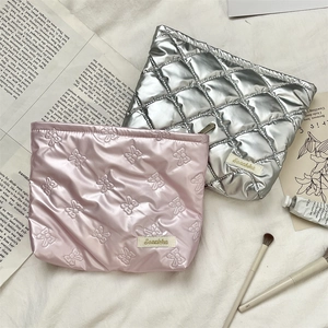 Detail of silver and pink quilted cosmetic bags with zip closure on fabric background