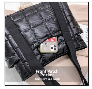 Close-up of black quilted puffer tote bag with front pocket showing a smartphone inside