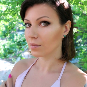 Gros plan de boucles d'oreilles émeraude avec base en argent portées par un mannequin