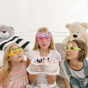 Three girls wearing colorful Happy Birthday paper glasses celebrating at a party