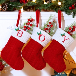Three red and white knit Christmas stockings with BOY embroidery hanging on a fireplace